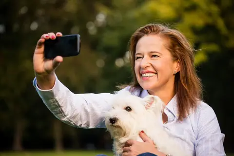 Smiling woman taking a selfie with her white terrier
